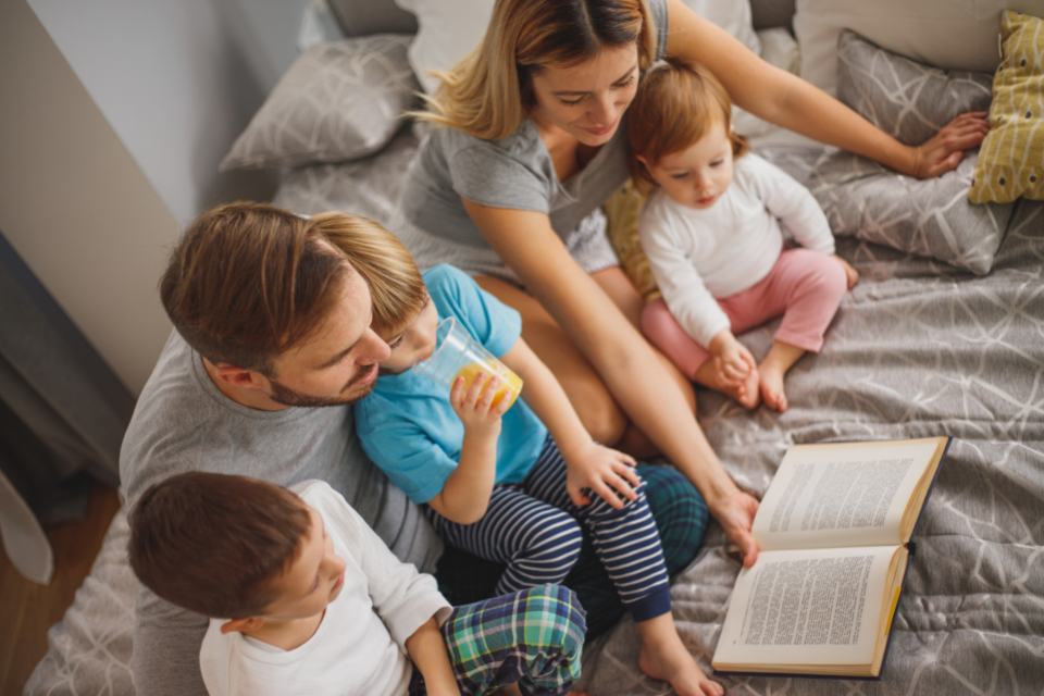 Une famille réunie dans le lit pour lire une histoire du soir